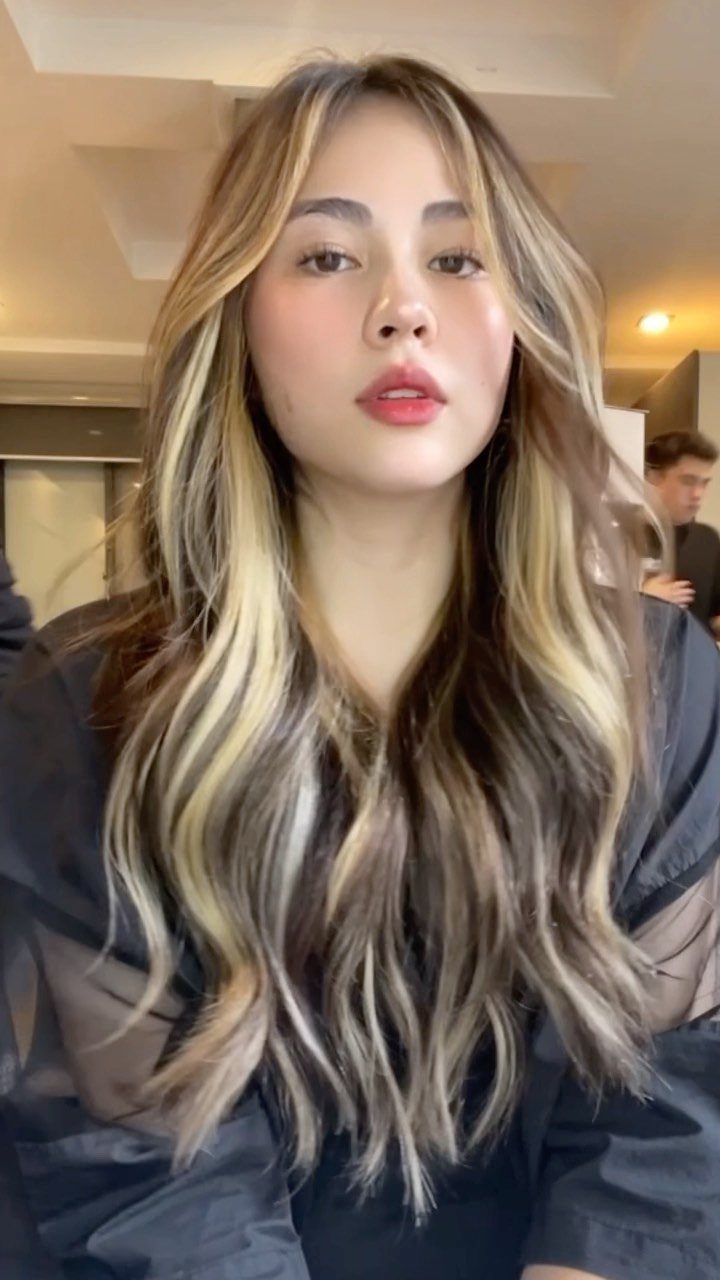 Woman with long brunette waves and bold blonde face-framing highlights