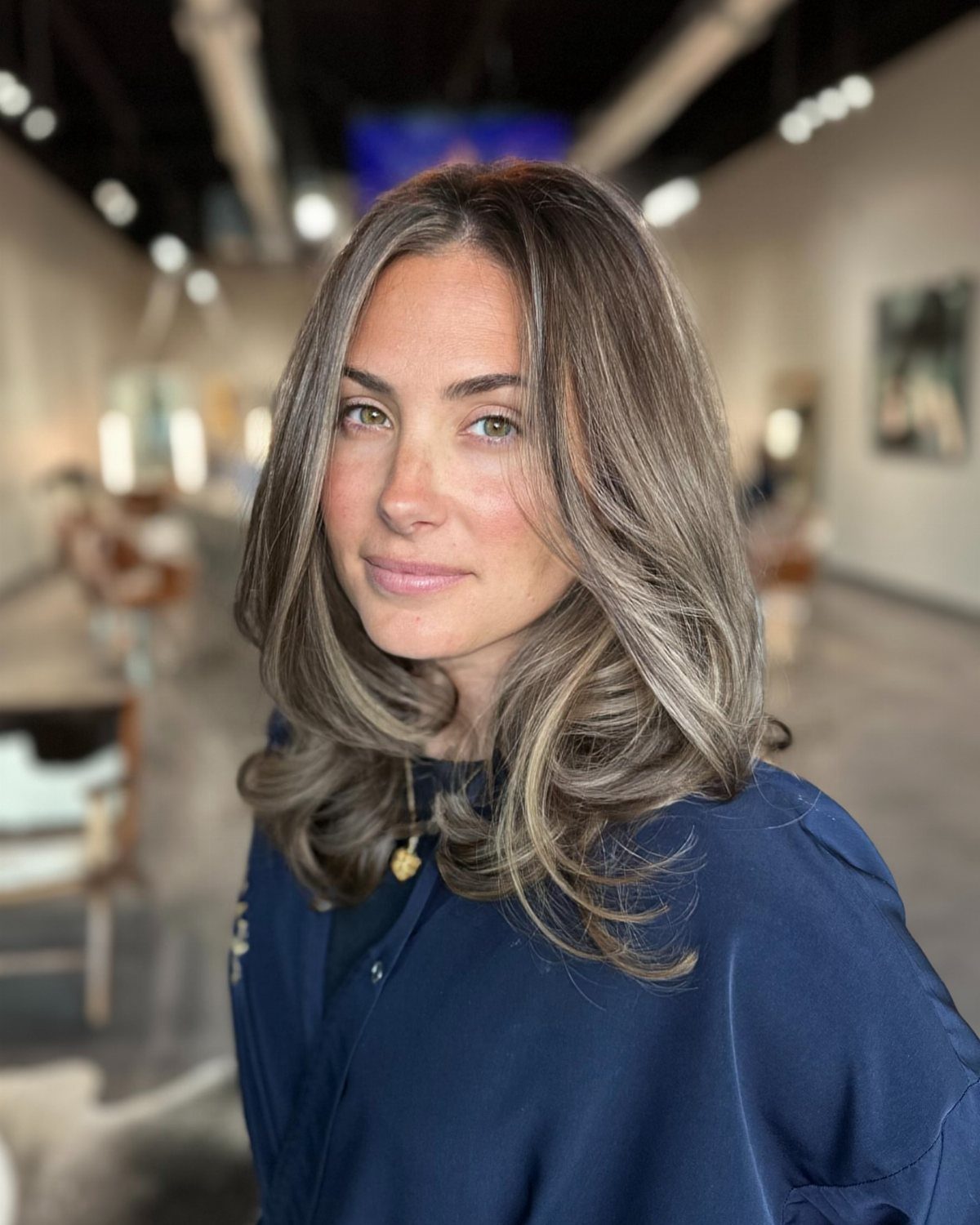 Woman displaying brunette hair with blended gray and blonde highlights in layered waves