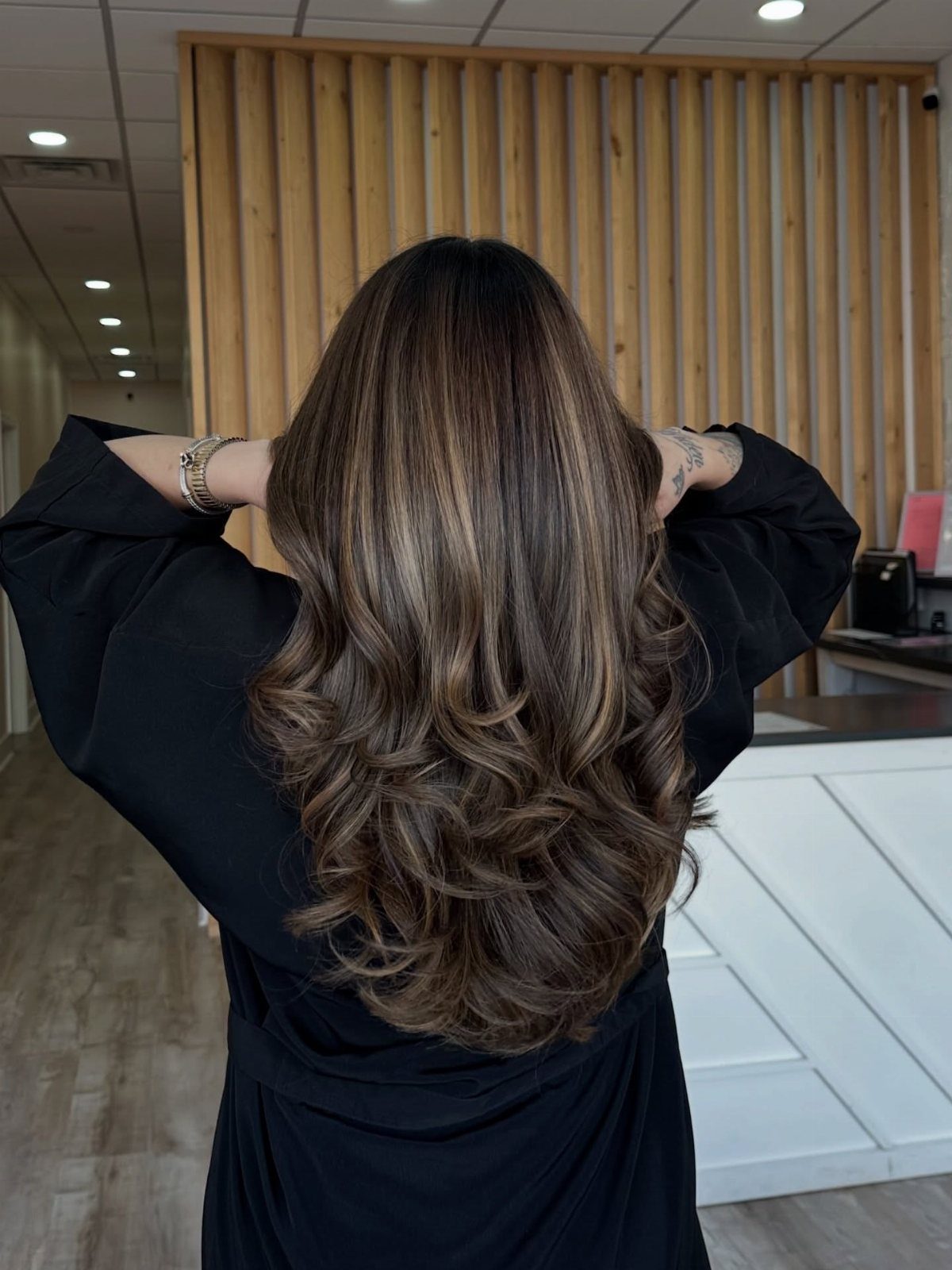 Long brunette curls with blended caramel and ash-blonde highlights in a salon
