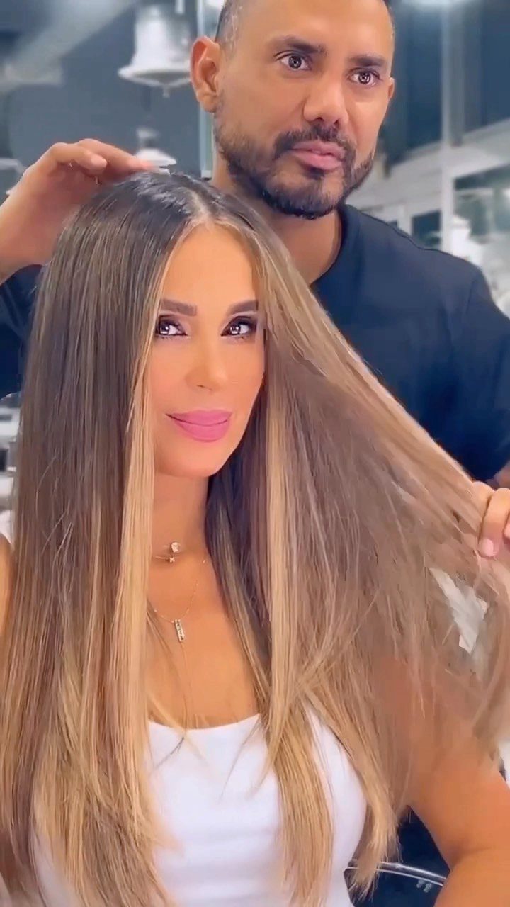 Woman showing long brunette hair with blended warm caramel-blonde balayage in a salon