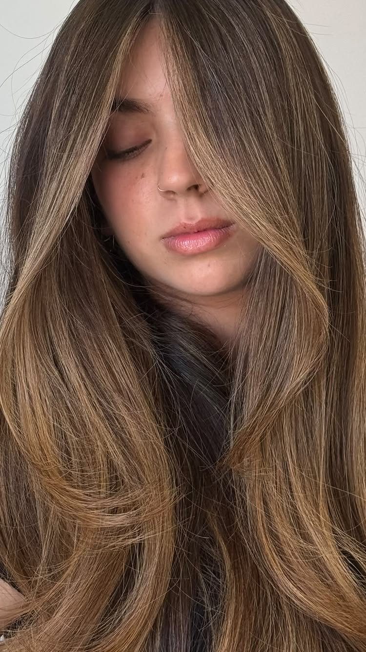 Woman with long brunette hair and caramel face-framing highlights
