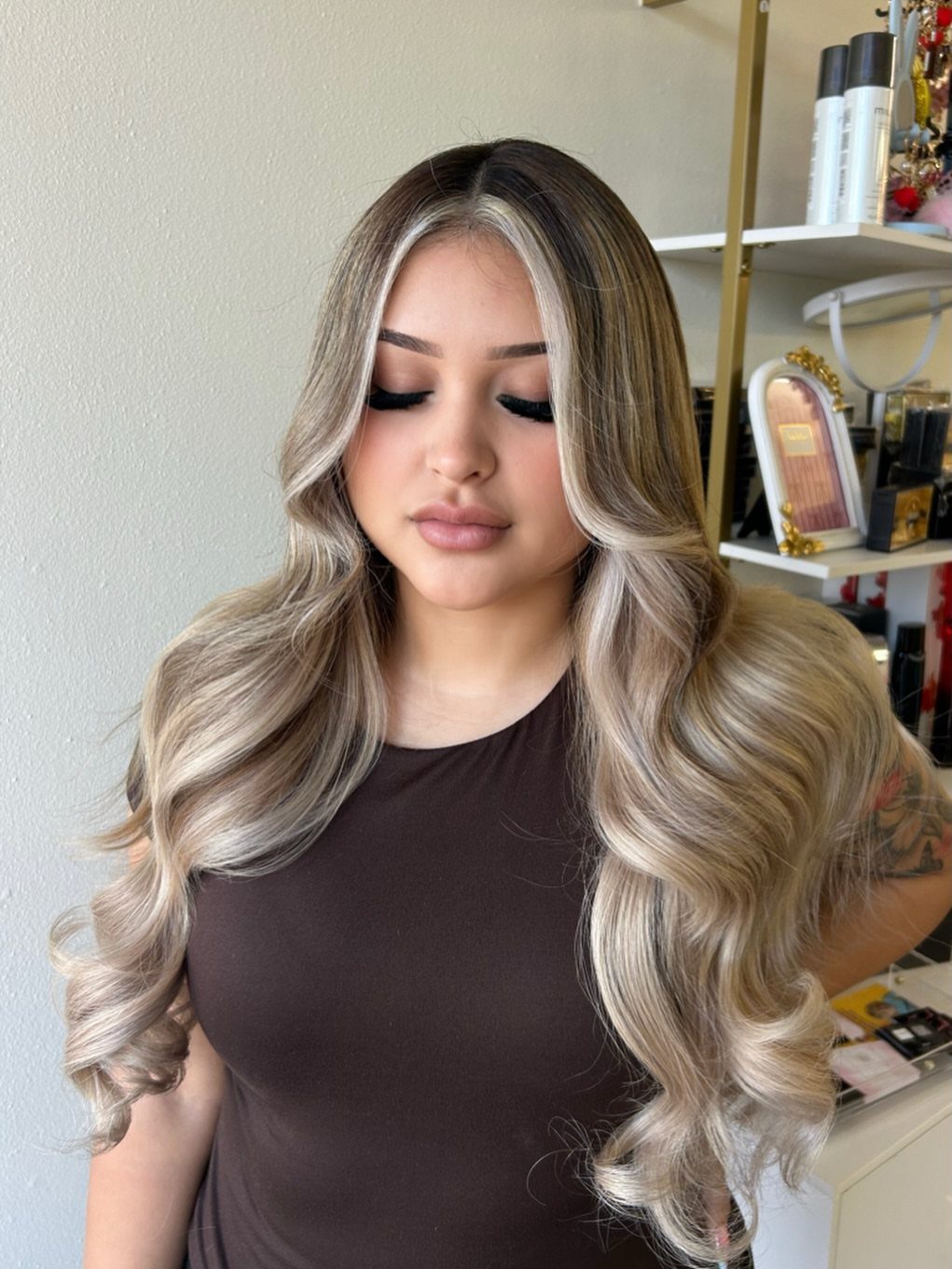 Woman with brunette roots and cool ash-blonde highlights in long curls