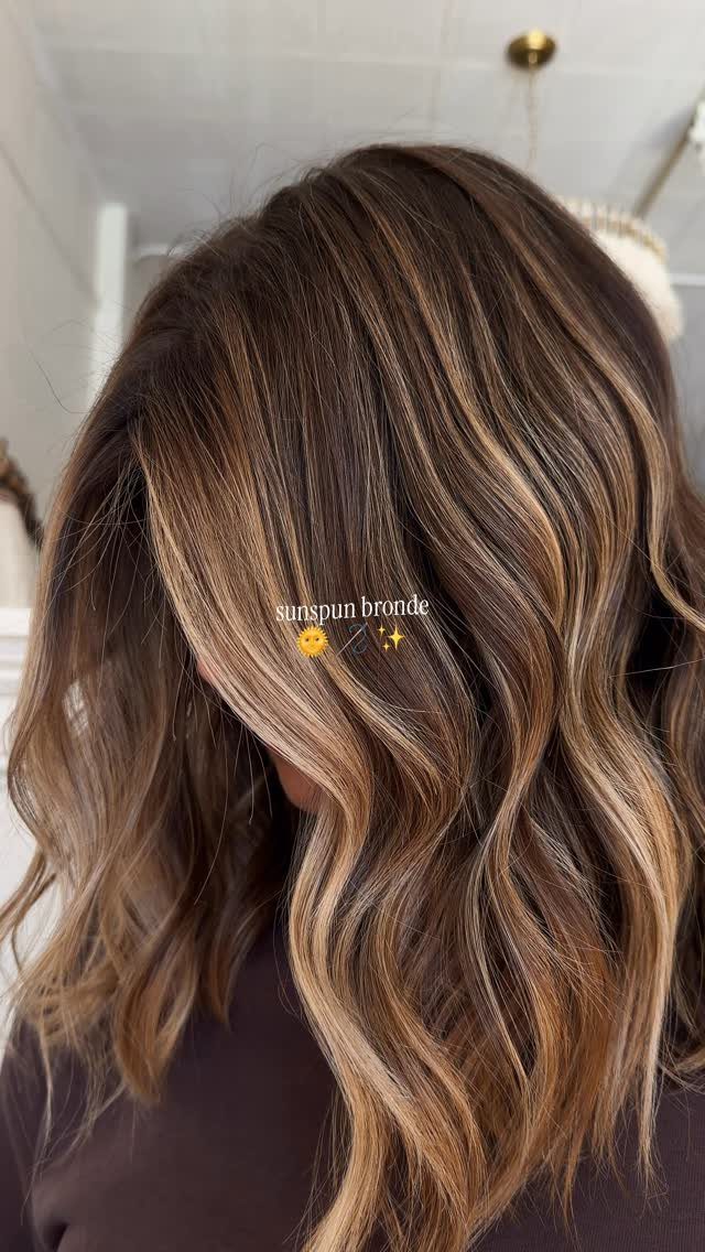 Wavy brunette hair with fine blonde highlights scattered through the lengths