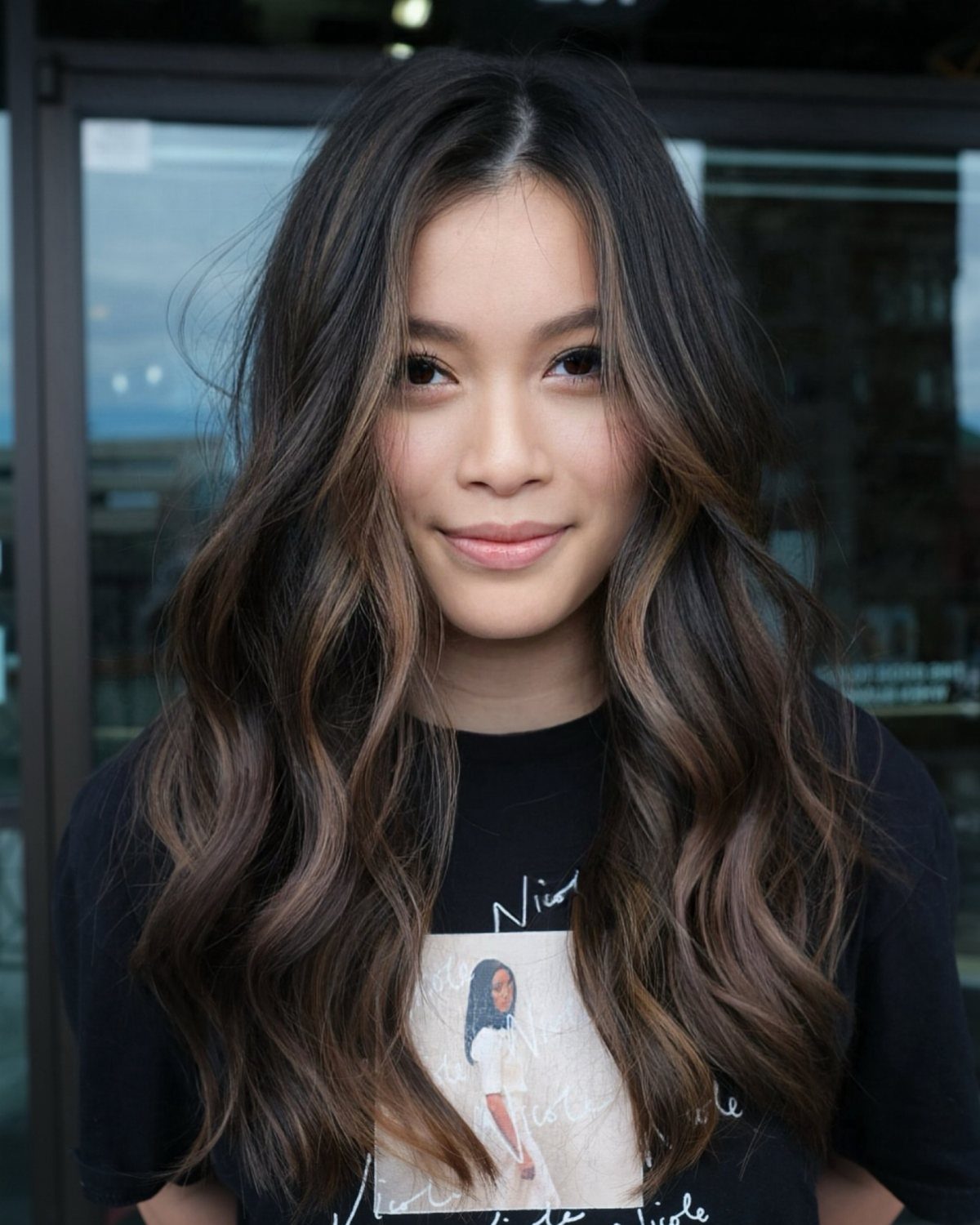 Woman showing long brunette waves with subtle stonewashed graduated balayage highlights