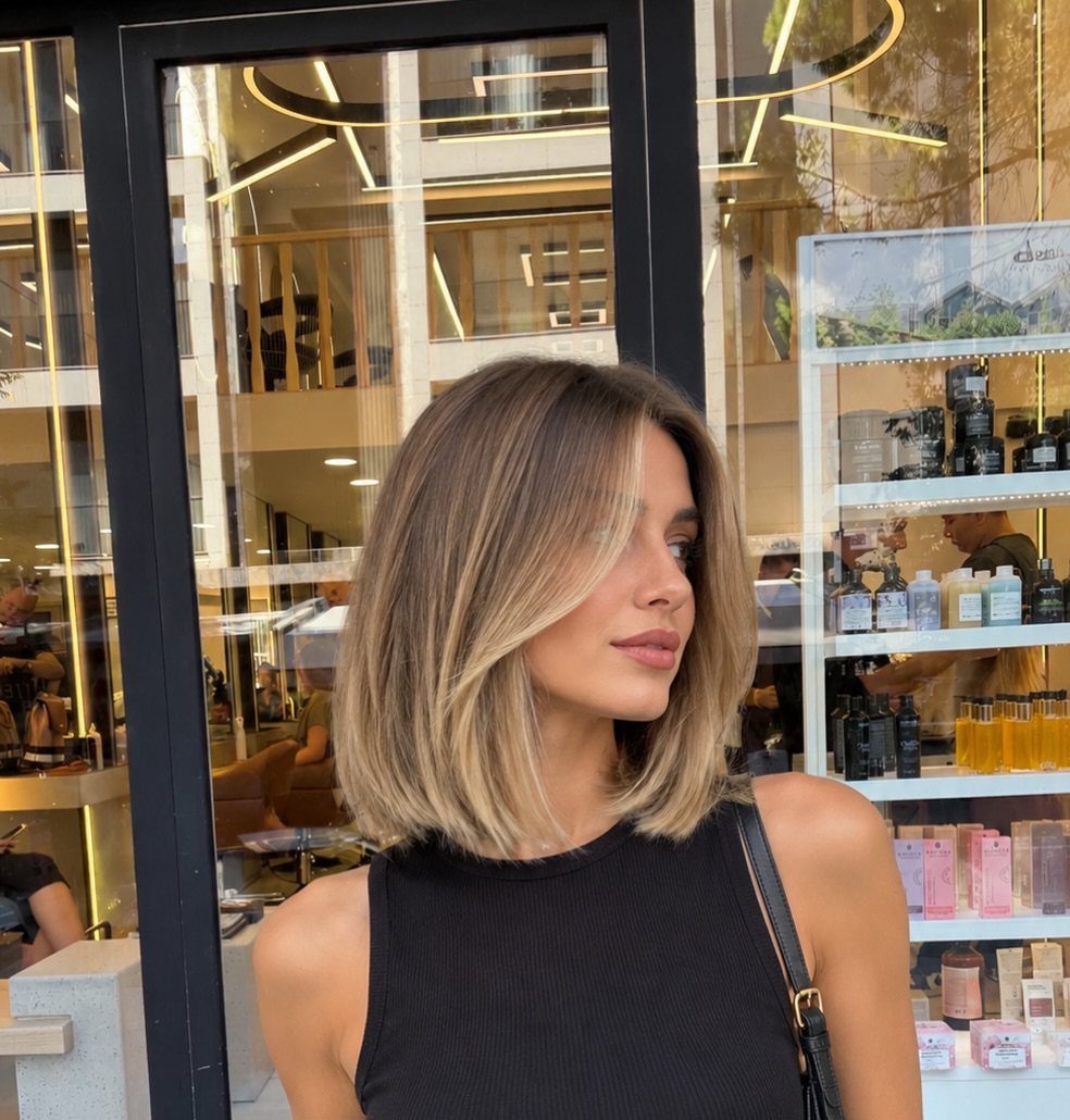 Woman showing a chin-length brunette bob with warm blonde balayage highlights
