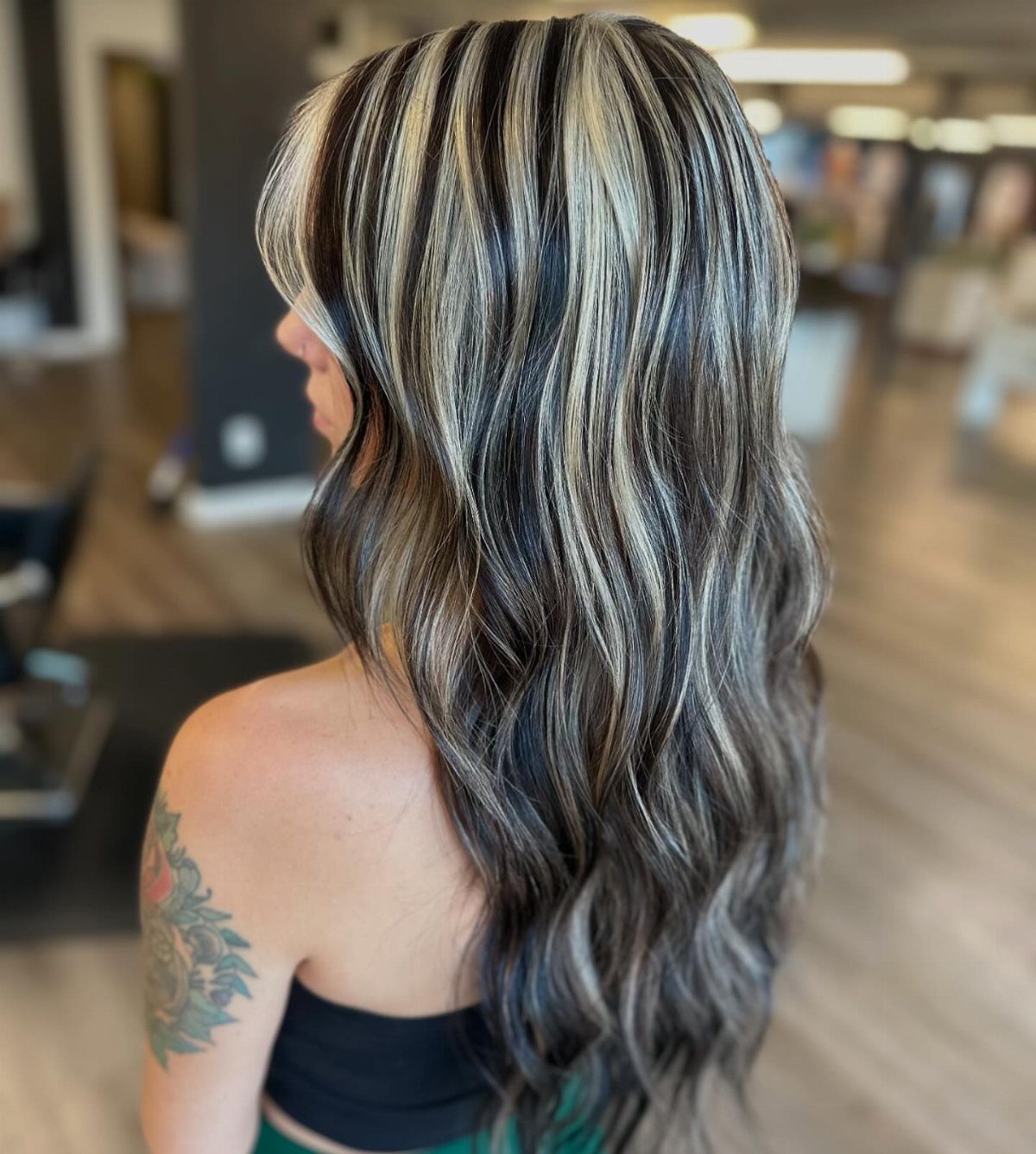 Long wavy black hair with chunky silver-white streaks shown from behind