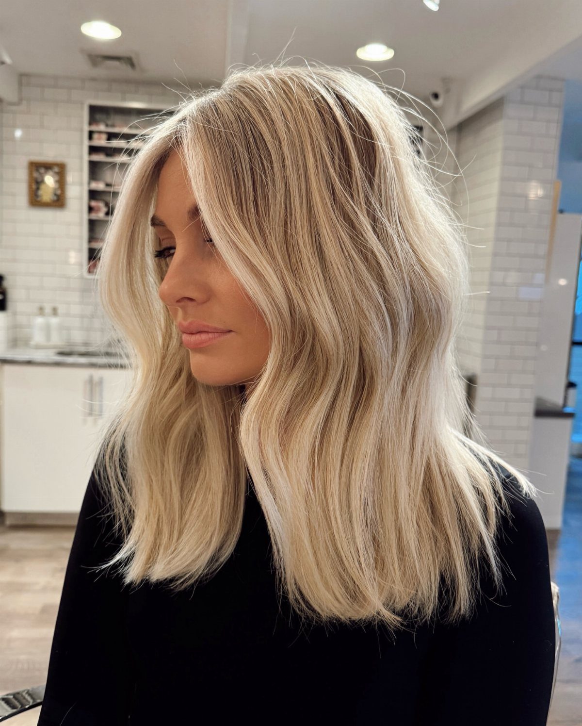 Blonde lob with pale ribbon highlights and loose waves in a salon