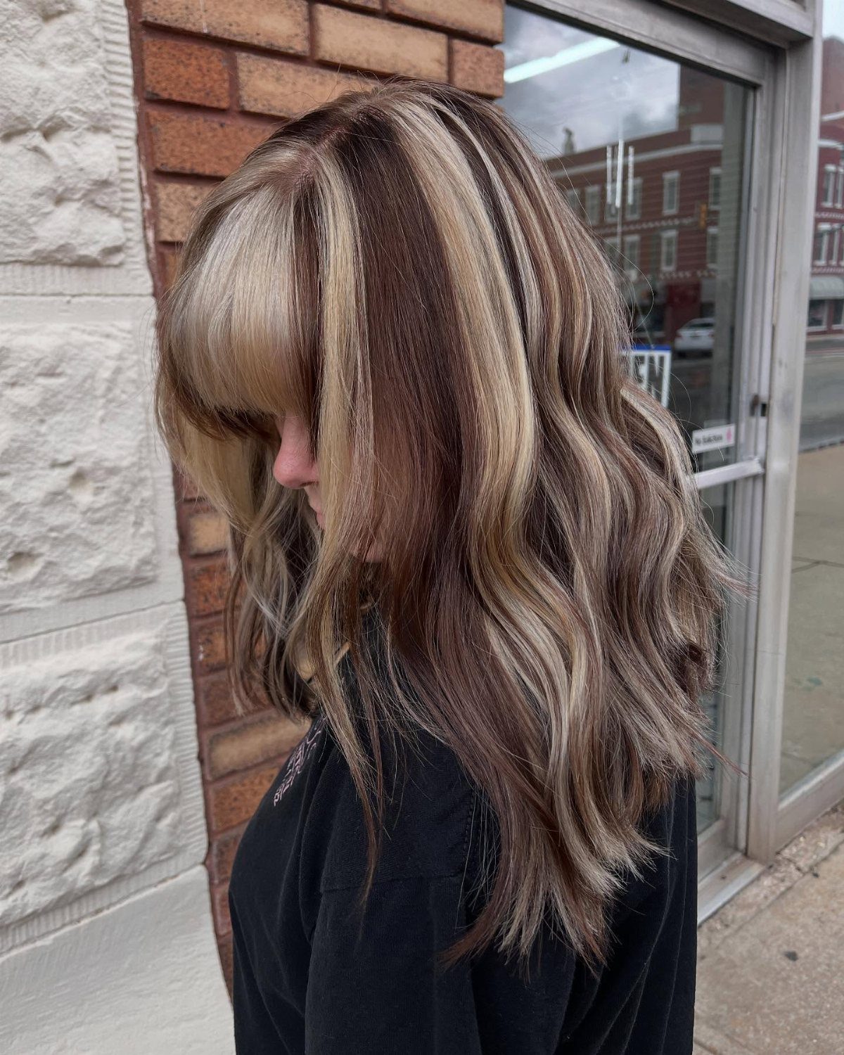 Wavy brown hair with chunky blonde highlights and full bangs