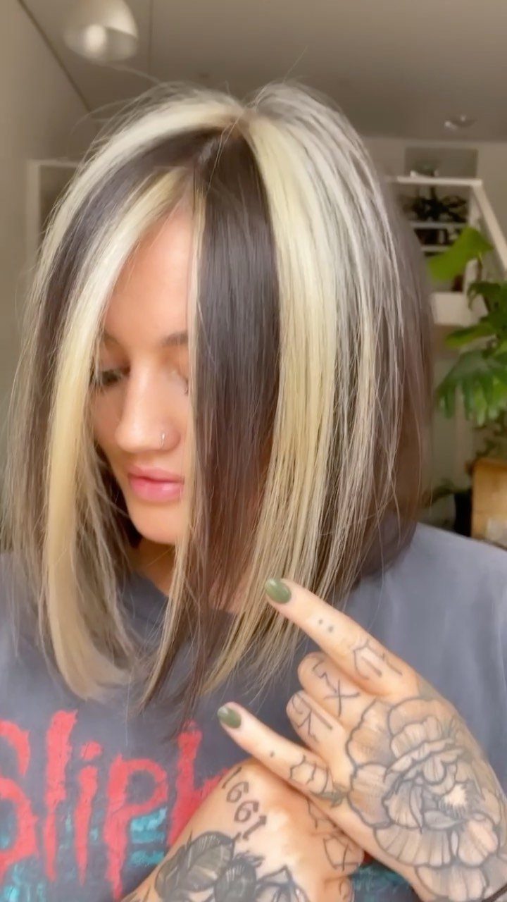 Chunky blonde and silver highlights frame straight dark-rooted shoulder-length hair