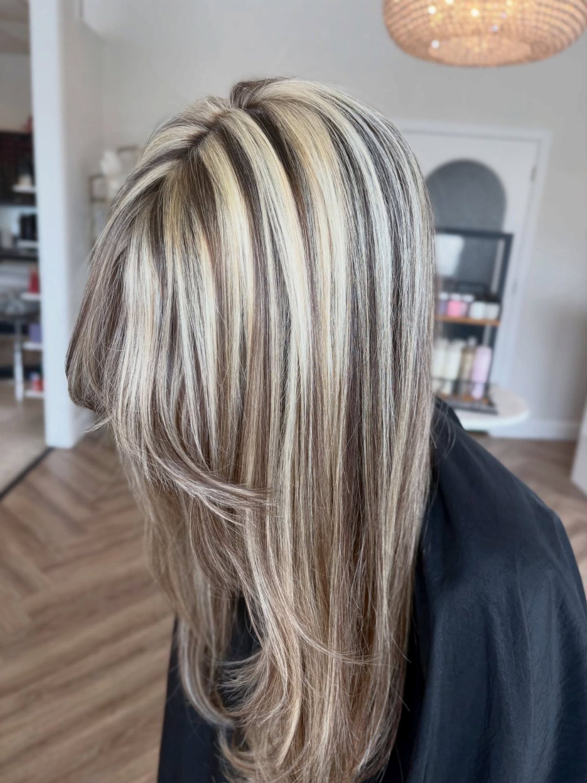 Layered hair with chunky blonde highlights and dark contrasting roots in a salon