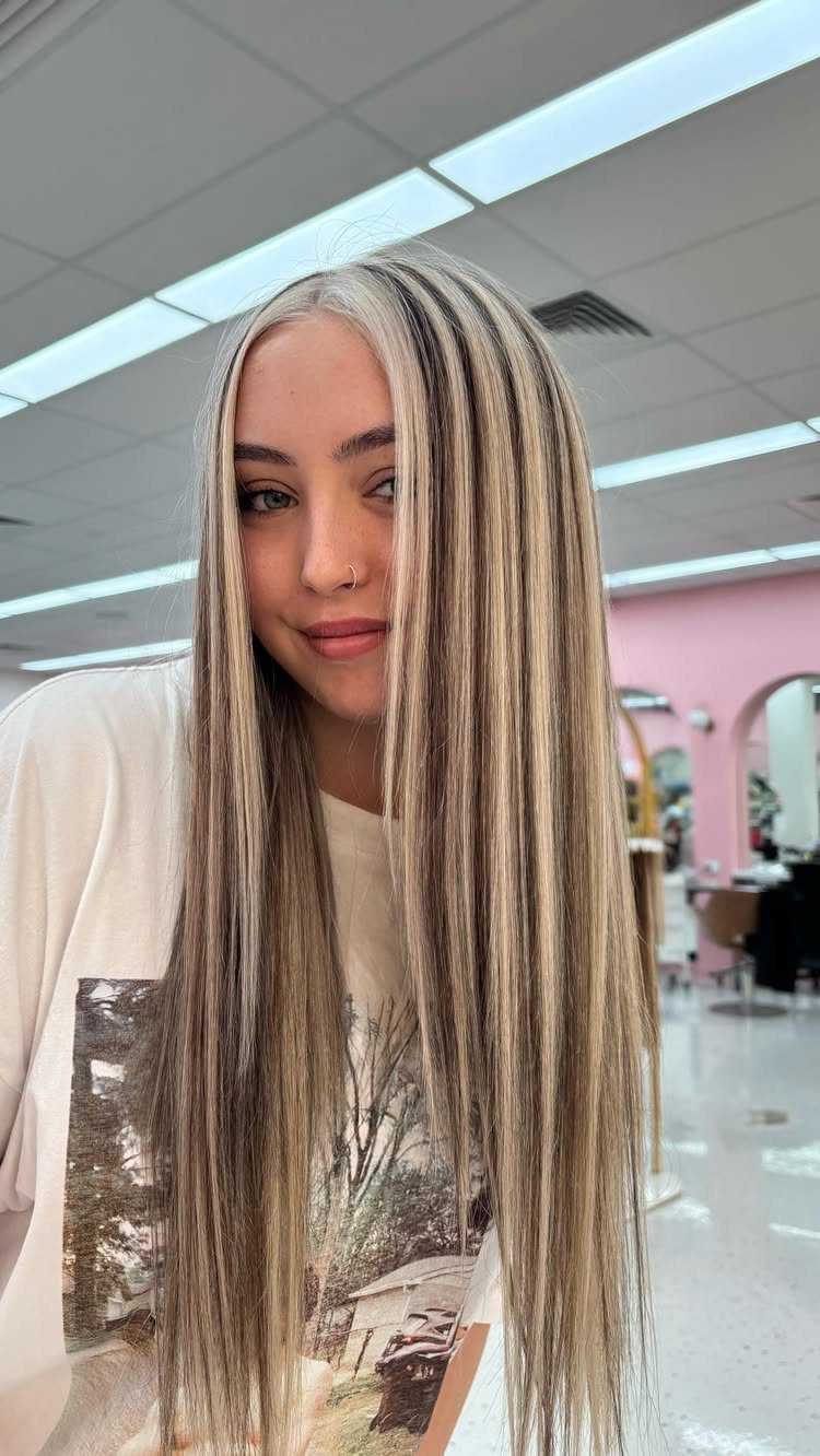 Long straight brown hair with thick pale blonde highlights in a salon