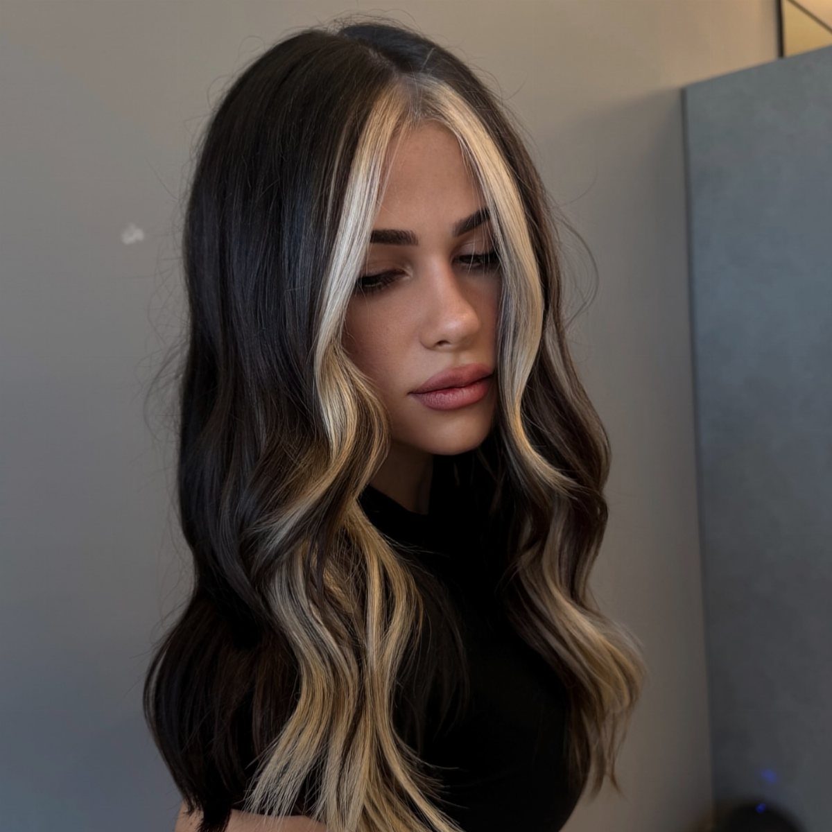 Woman with long dark waves and chunky blonde ribbons framing her face