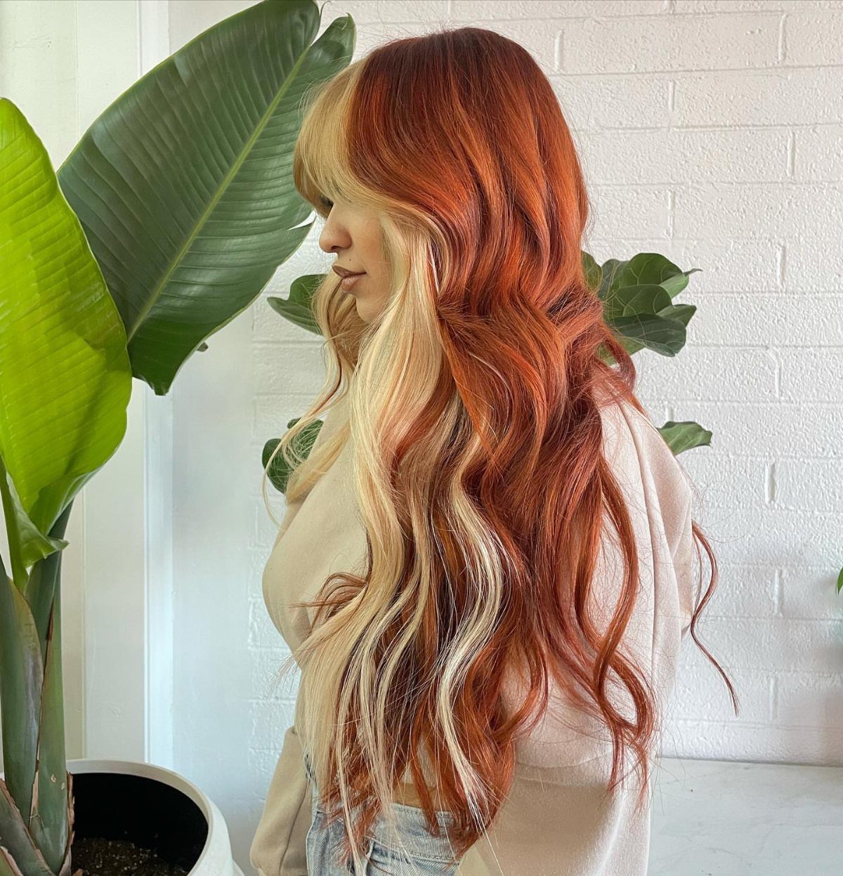 Woman with long copper-red waves and broad pale blonde front highlights