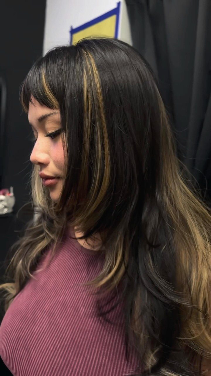 Woman with long dark hair, wispy bangs, and a chunky blonde front streak
