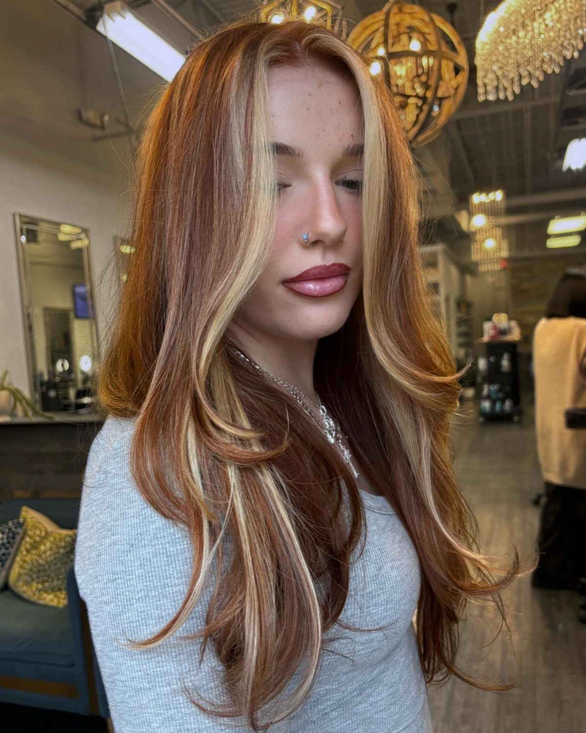 Woman with long copper hair and broad golden blonde highlights in a salon