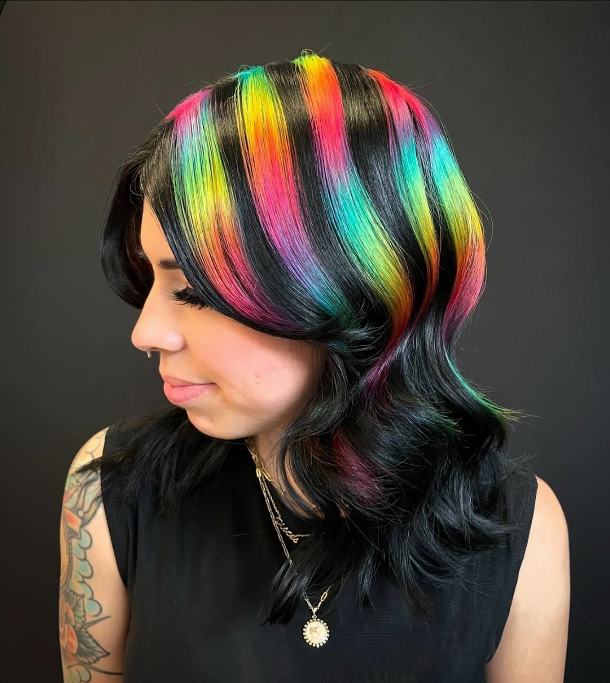 Woman with long black hair and chunky rainbow-colored highlights