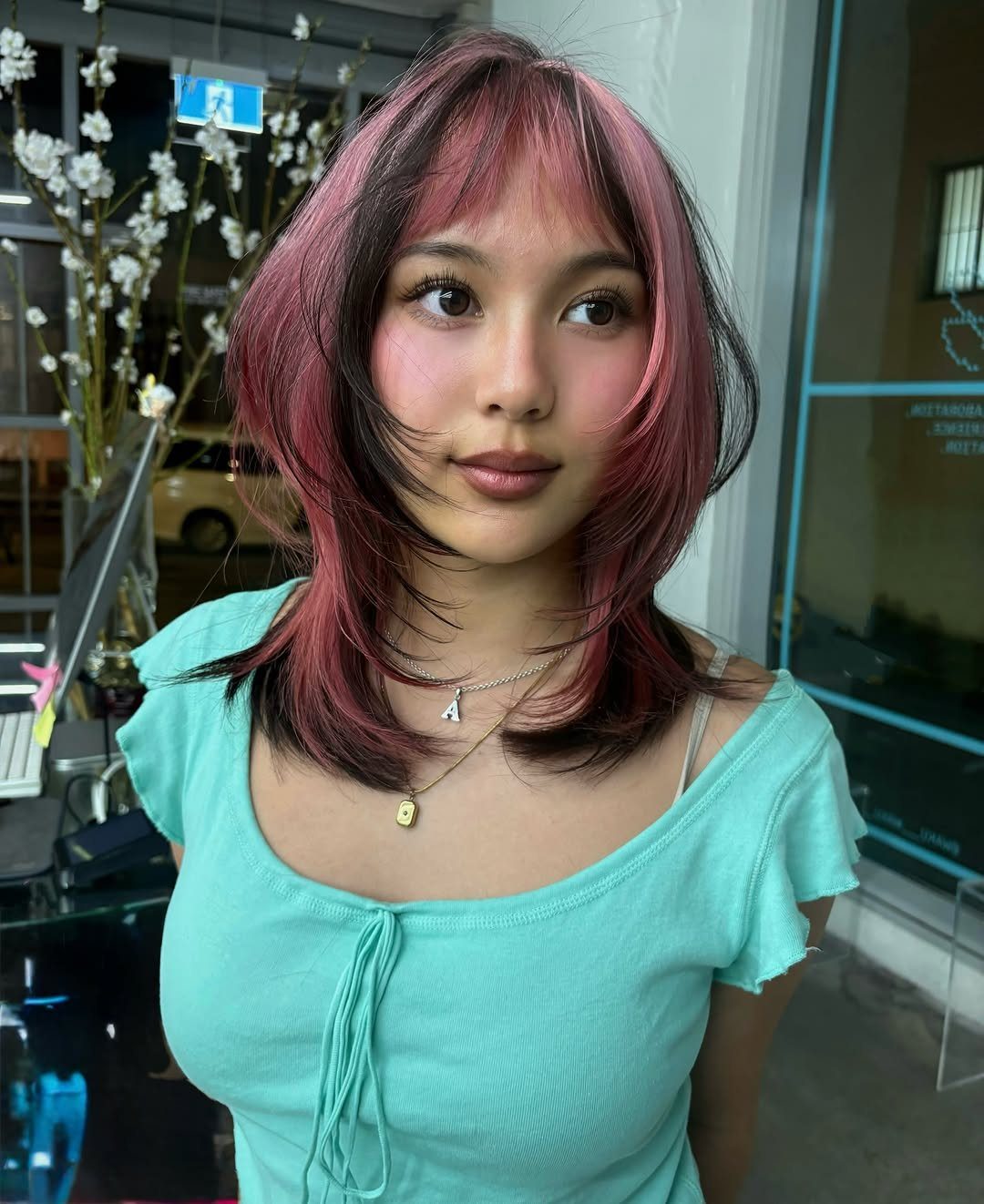 Woman with shoulder-length dark hair featuring vivid pink chunky highlights