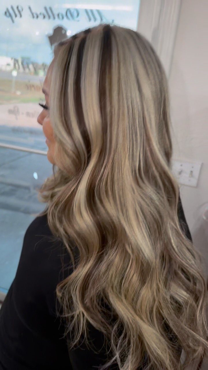 Long wavy blonde hair with broad platinum highlights and darker sections