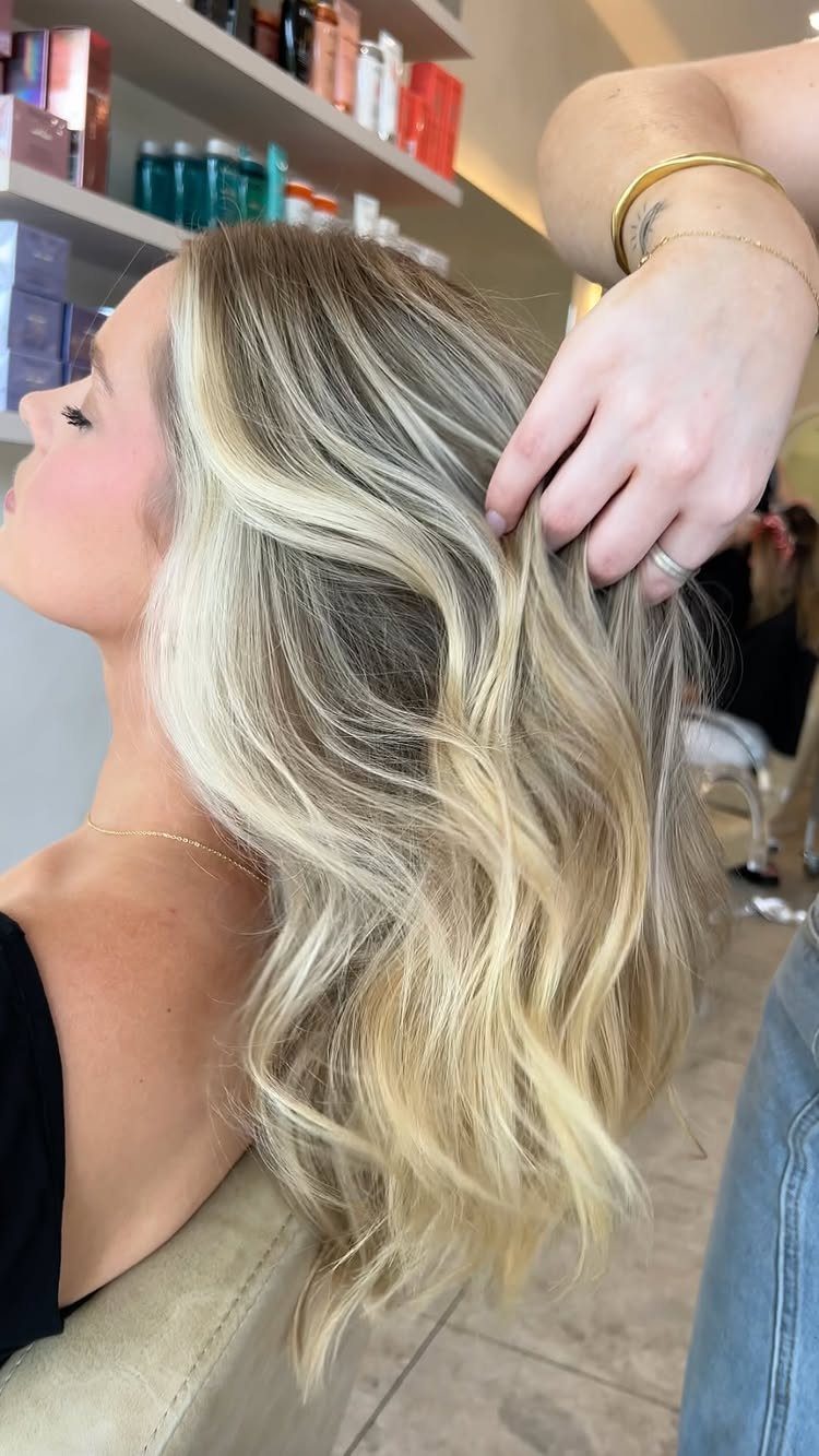 Long wavy blonde hair with broad pale highlights lifted by a stylist