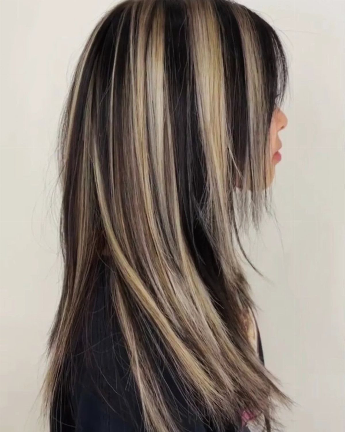 Long dark hair with contrasting chunky blonde highlights shown in side profile