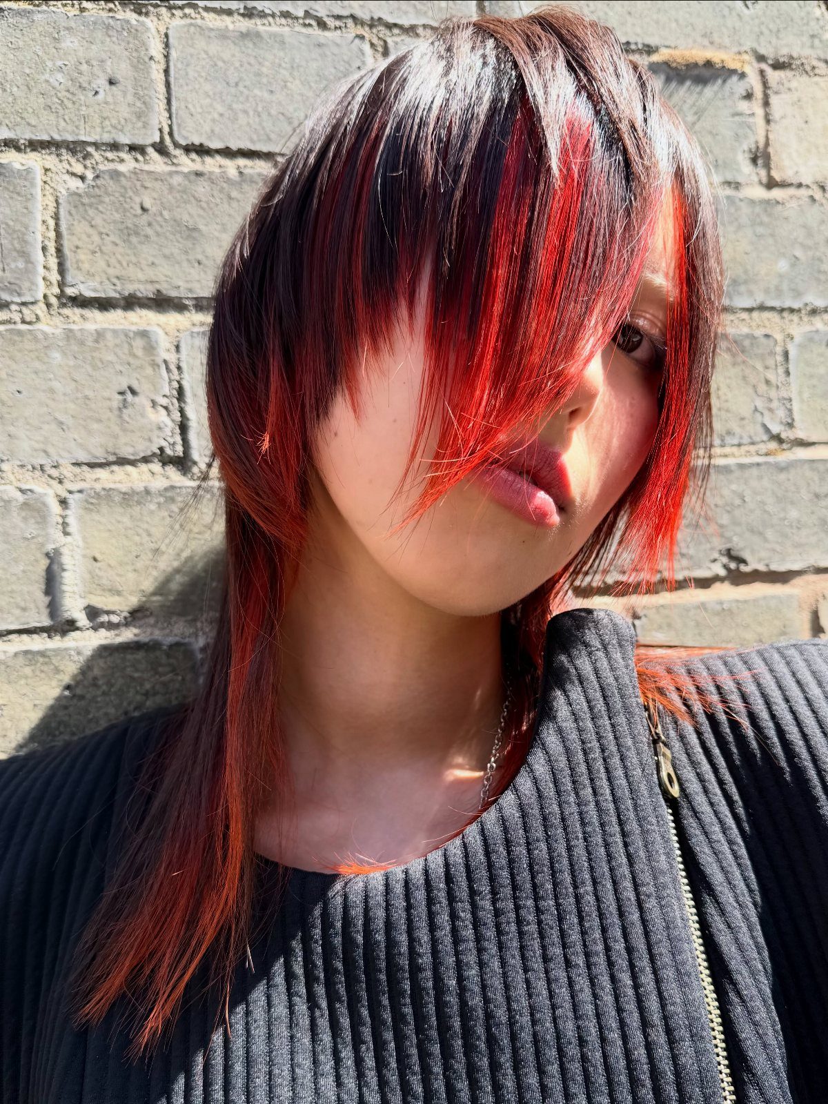 Person with layered dark hair and bold red and white highlights