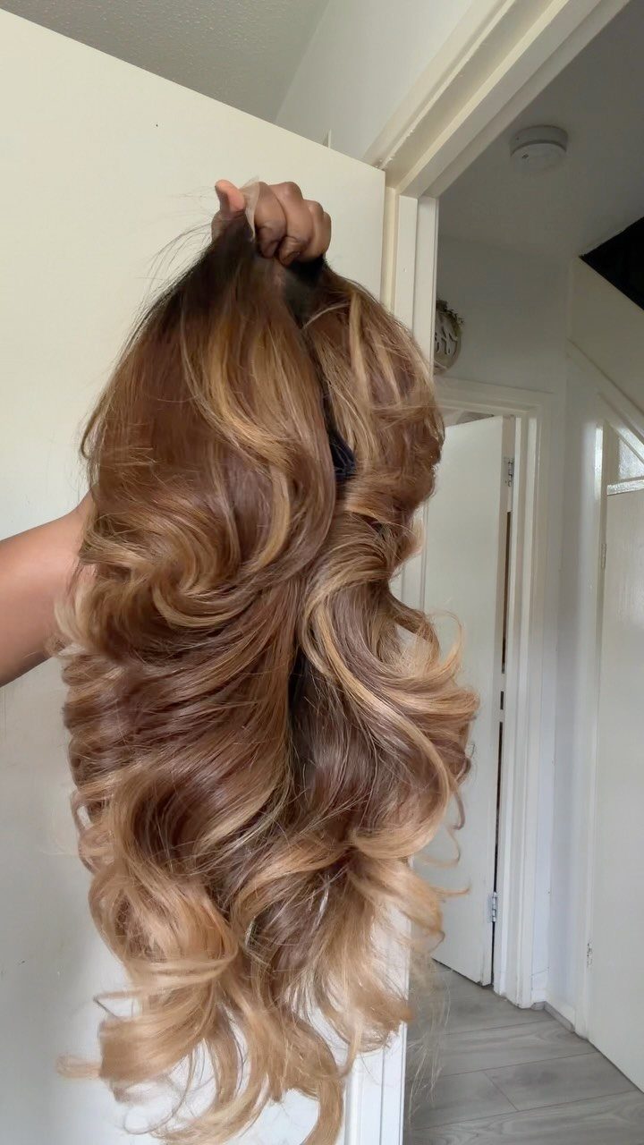Curled hair transitions from dark brown roots to caramel and blonde ends