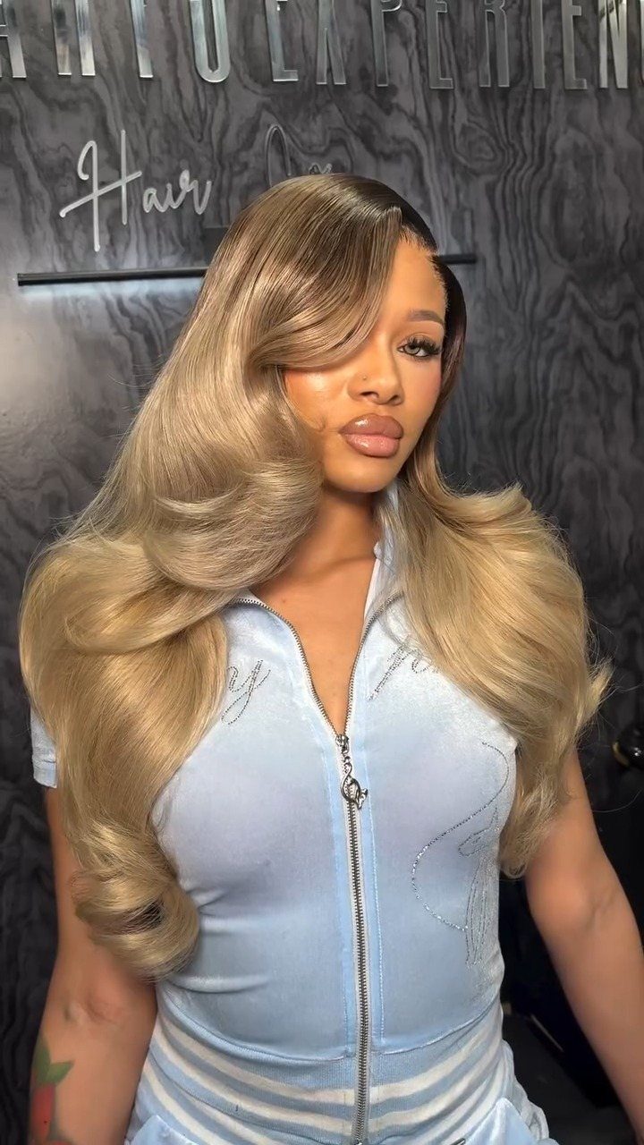Woman with long, wavy dirty blonde ombre hair and dark roots
