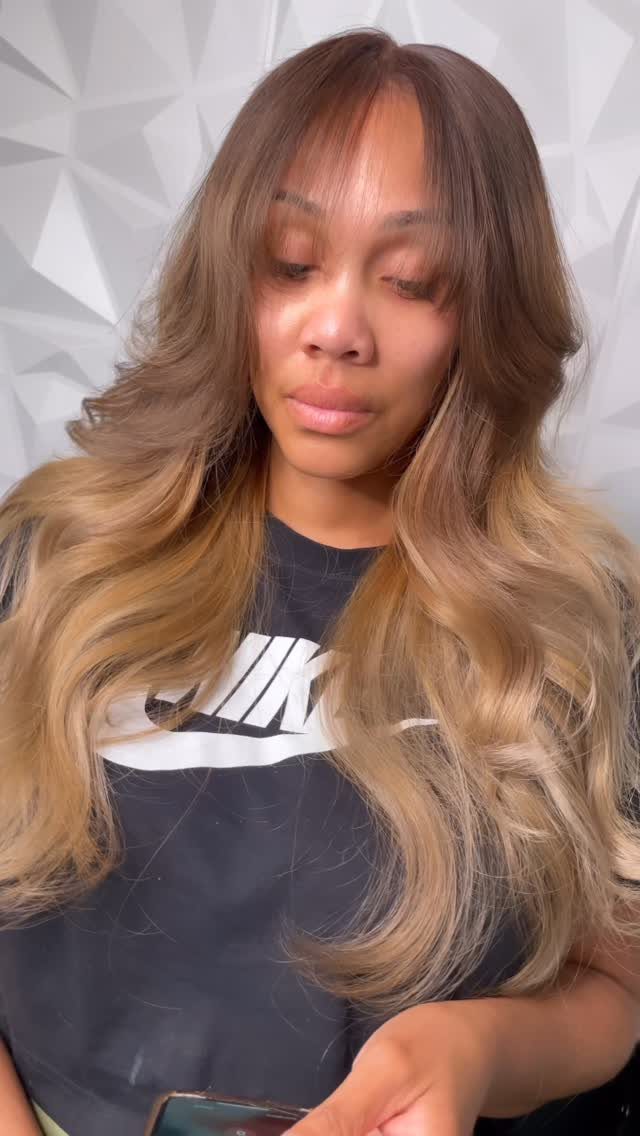 Woman with wispy bangs and long brown-to-blonde ombré waves