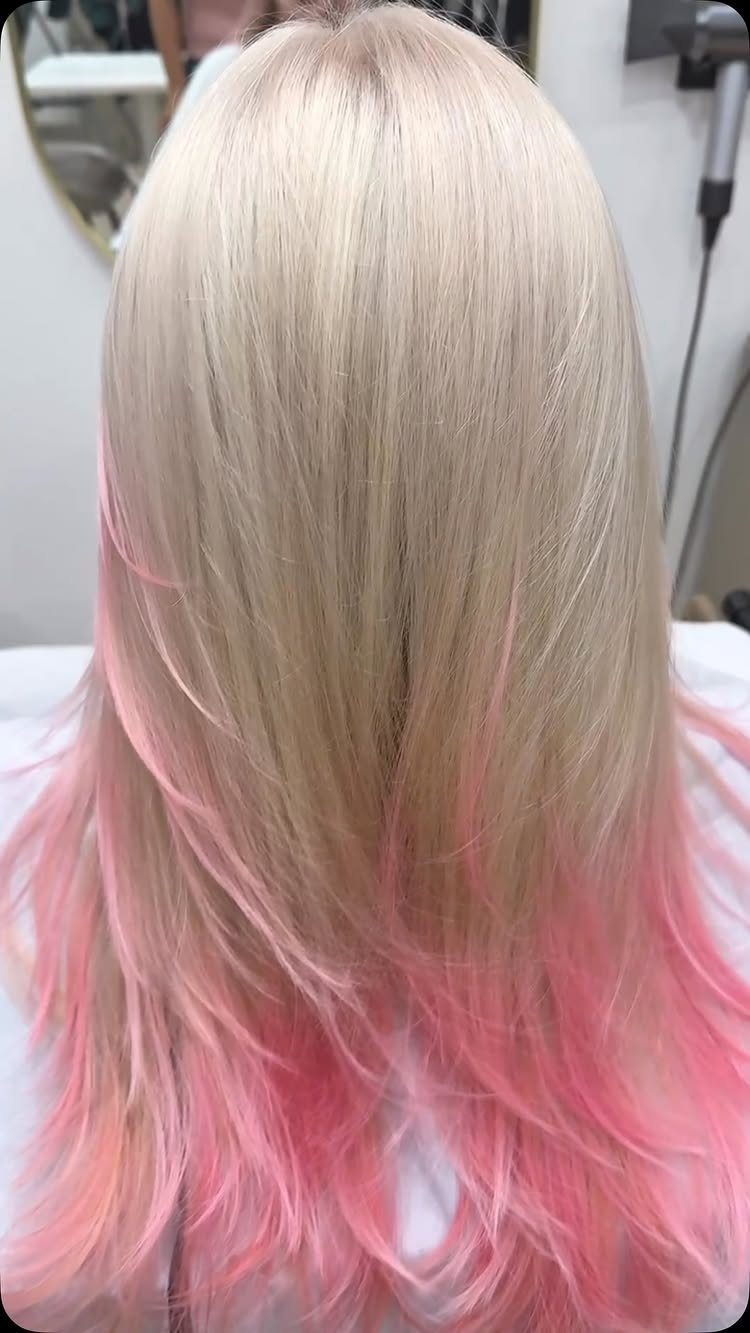 Platinum blonde hair fading into pink at the curled ends