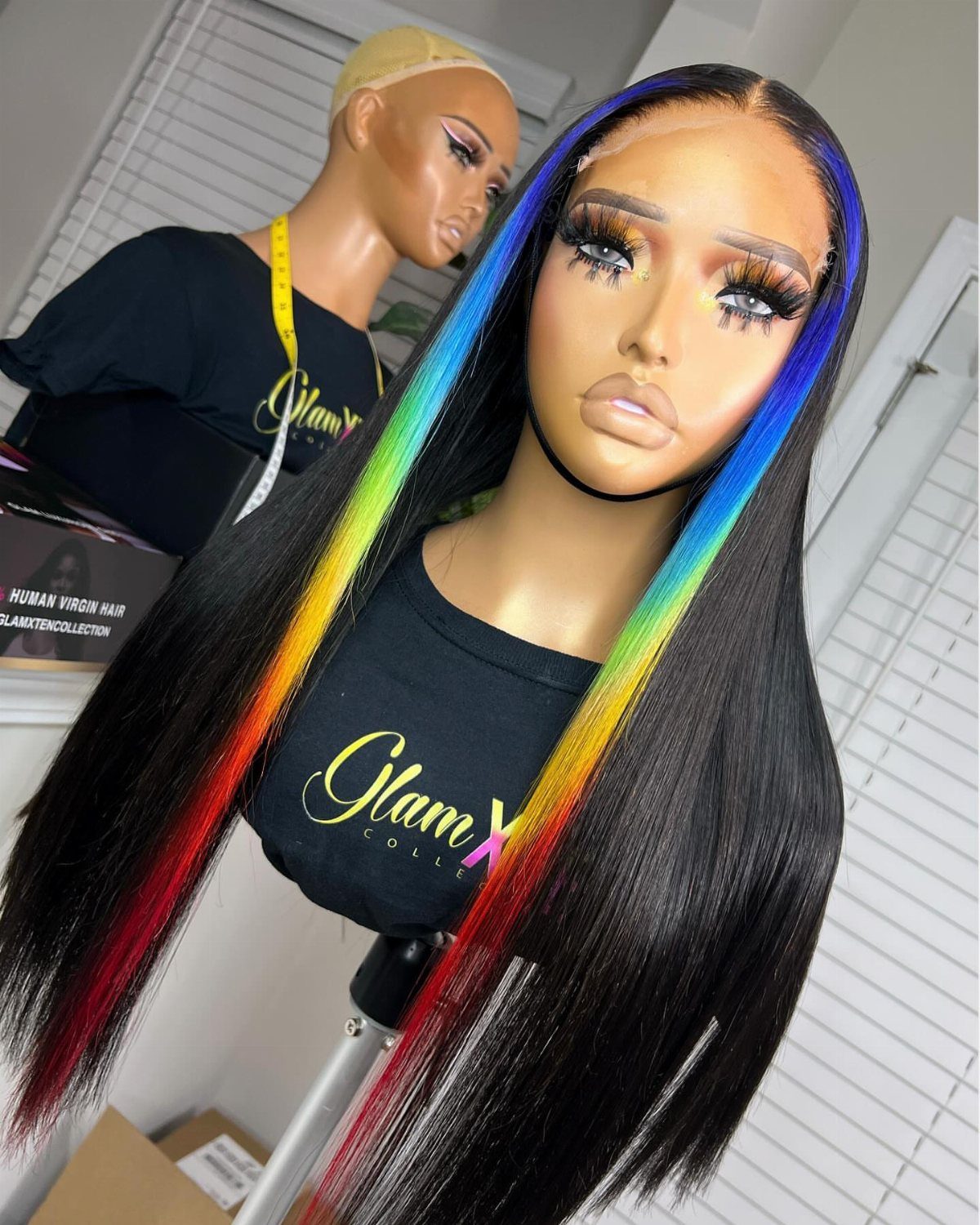 Mannequin heads display long black hair with vivid rainbow-colored front streaks.