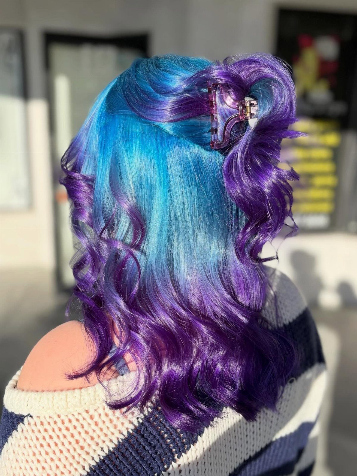 Curled turquoise and purple ombre hair clipped up at the crown