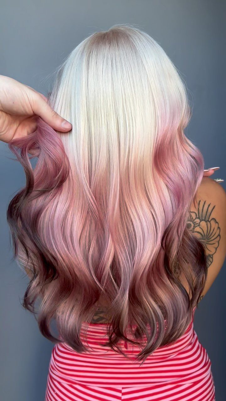 Long wavy hair fades from pale blonde through pink to mauve-brown ends