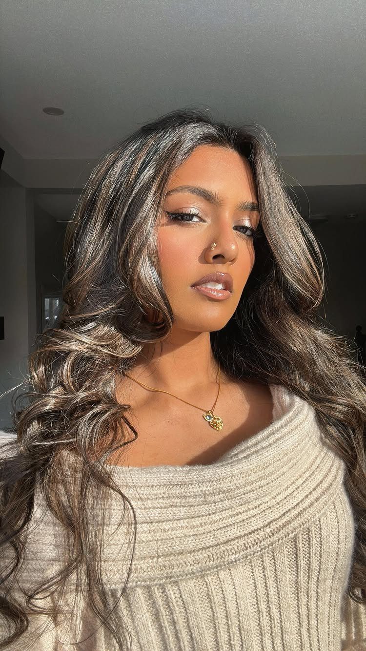 Woman with long, softly highlighted dark brown hair in loose waves