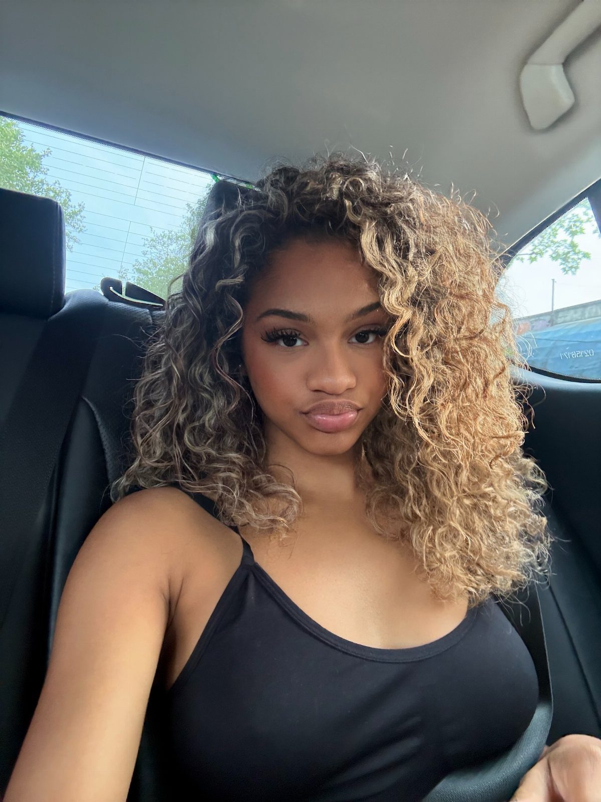 Woman displaying long curly dark brown hair with contrasting blonde balayage highlights