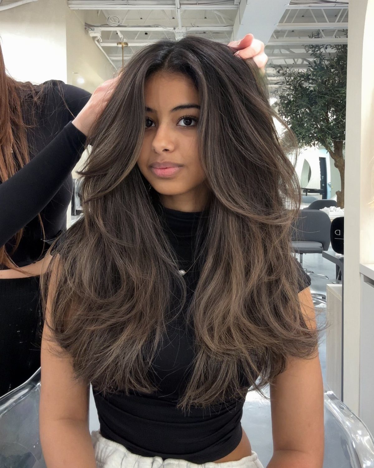 Woman with long dark brunette hair blended with lighter blonde balayage highlights