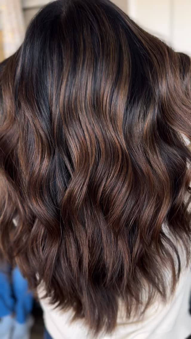 Wavy dark brunette hair with soft chestnut balayage highlights