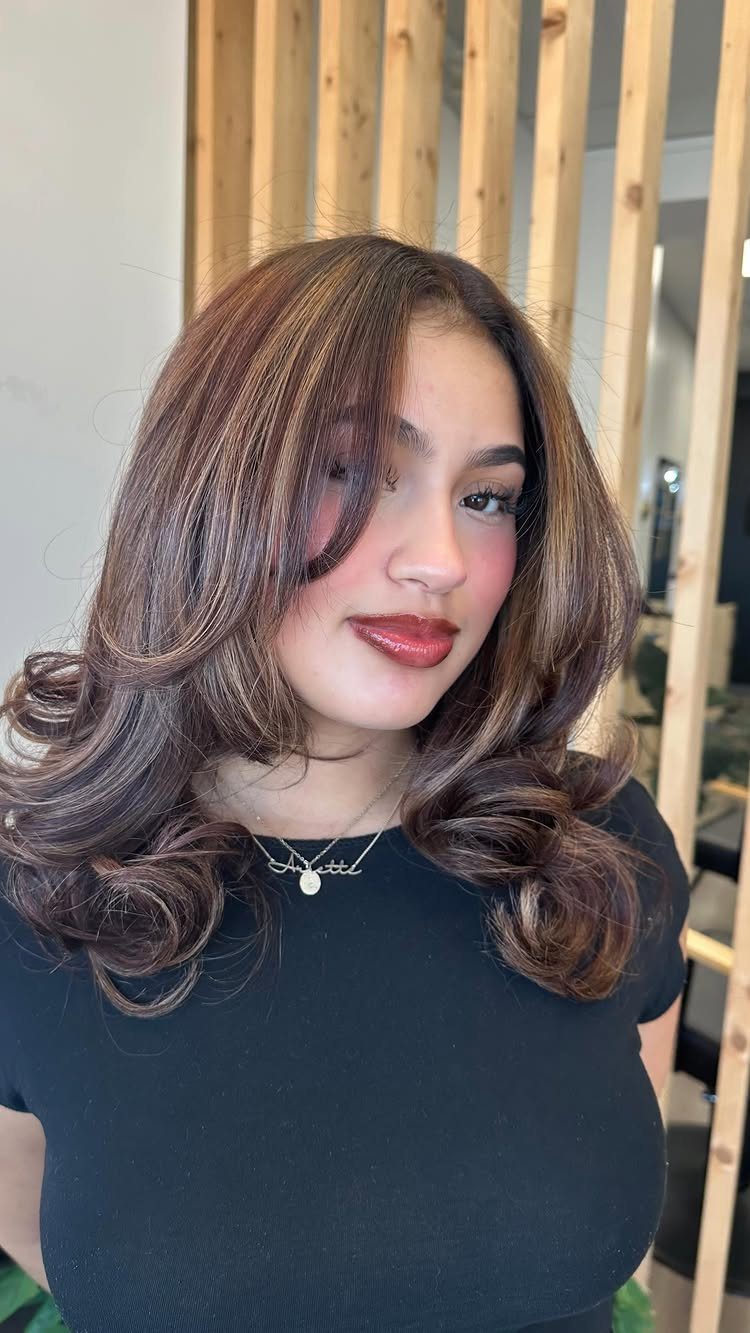 Woman showing voluminous chocolate caramel honey balayage in long wavy brunette hair
