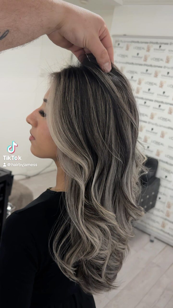 Woman displaying dark brown hair with ash-blonde highlights and curled ends