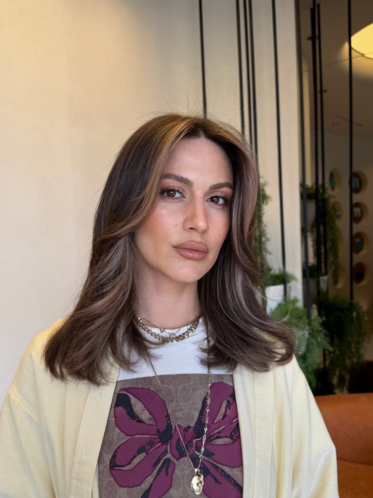 Woman with layered brunette hair and lighter face-framing highlights
