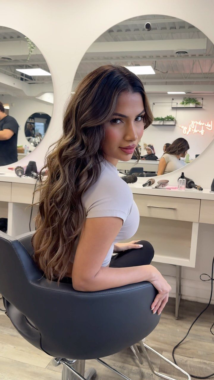 Woman showing long wavy dark brown hair with honey-brown balayage highlights