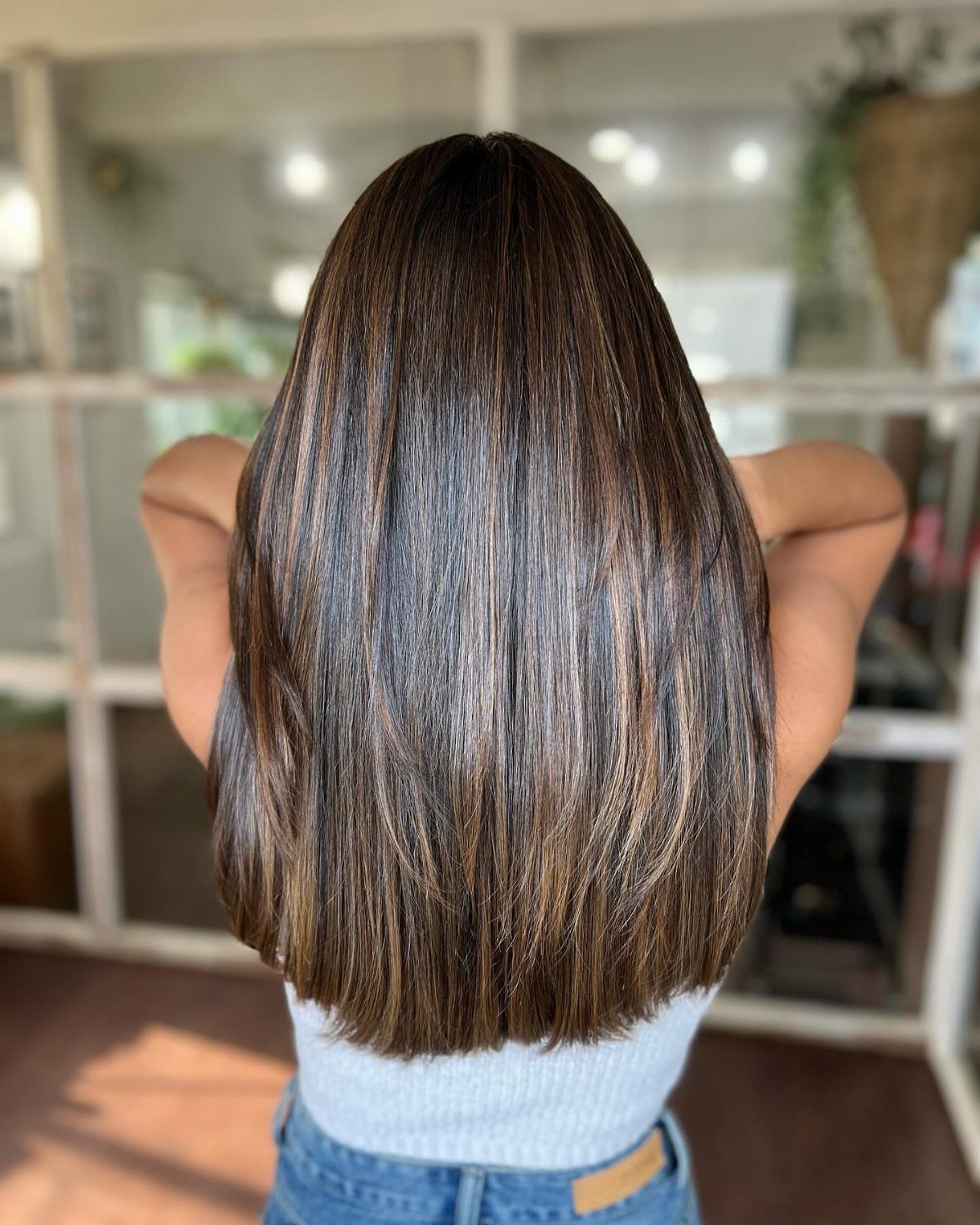 Straight brunette hair with subtle balayage highlights falls to the shoulders
