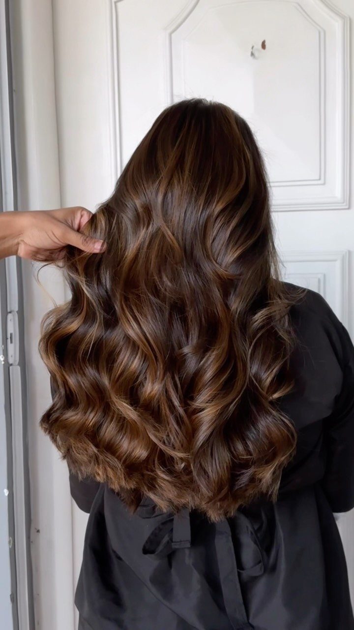 Long dark brown curls show soft, warm brown balayage highlights