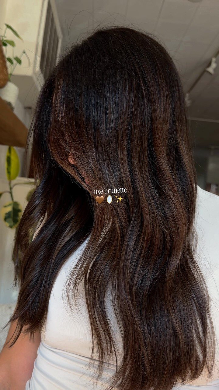 Long brunette hair shows subtle layered highlights and softly waved ends
