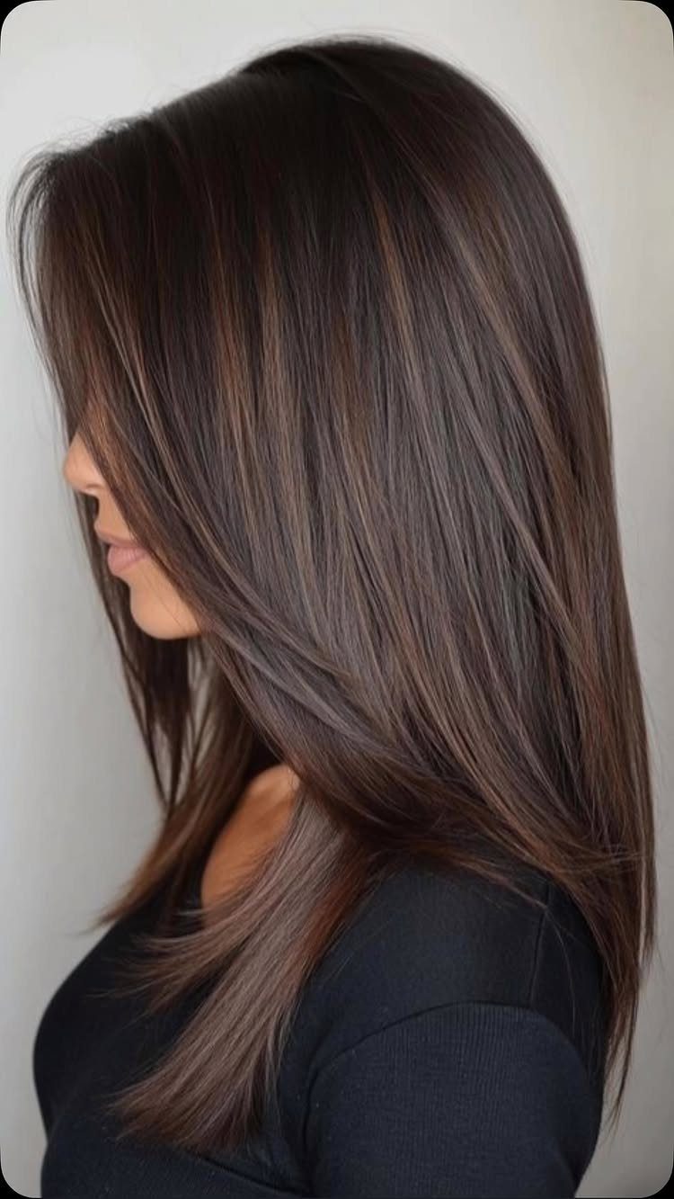 Long dark brown hair with fine beige-brown highlights swept smoothly over one shoulder