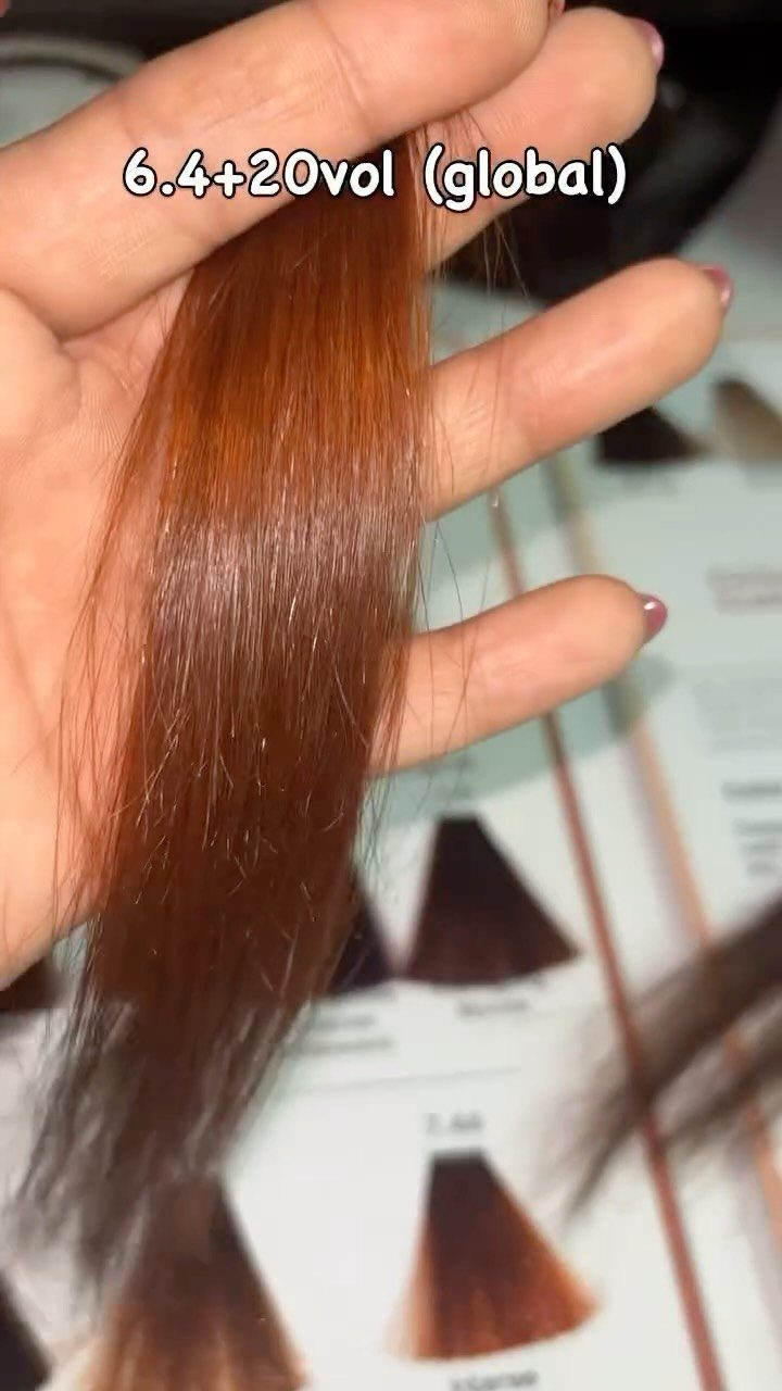 Chestnut-brown hair swatch held over a printed hair color chart
