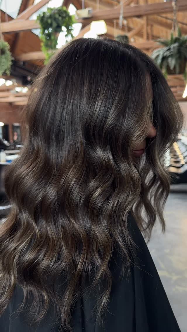 Long dark brown waves with subtle lighter strands in a salon