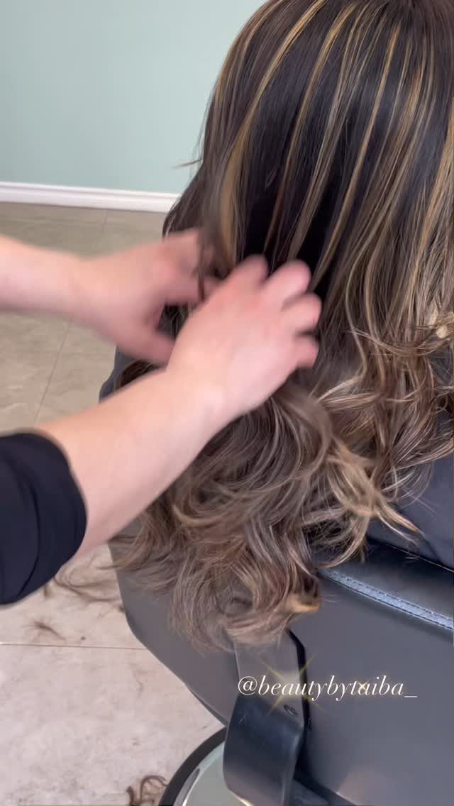 Dark brown hair with golden blonde highlights and curled ends in a salon