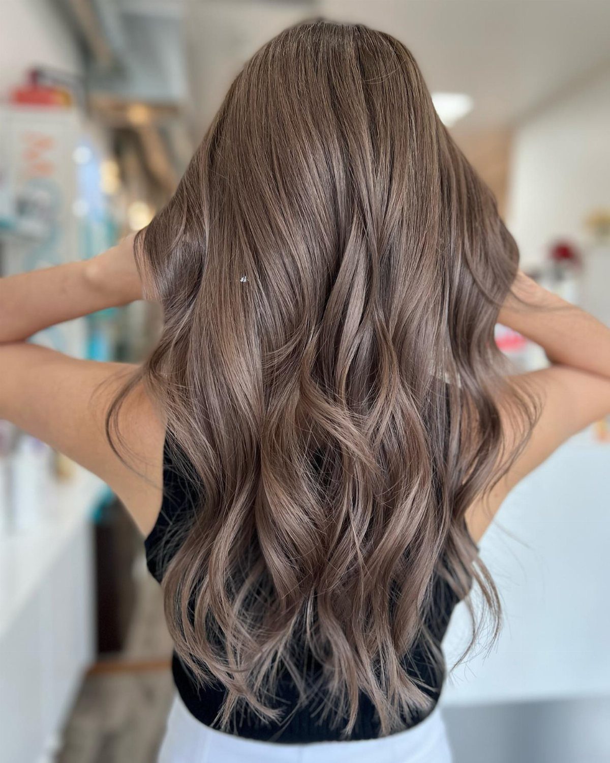 Long wavy mushroom brown hair with subtle gray-brown highlights in a salon