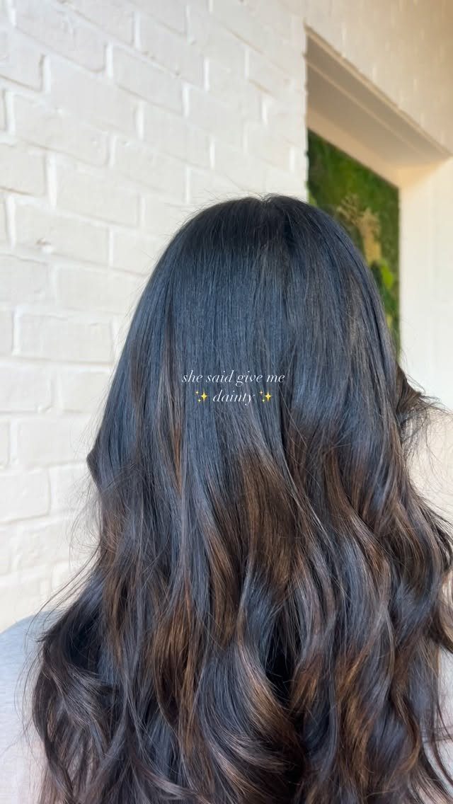 Long dark brown hair with fine highlights falling in loose waves