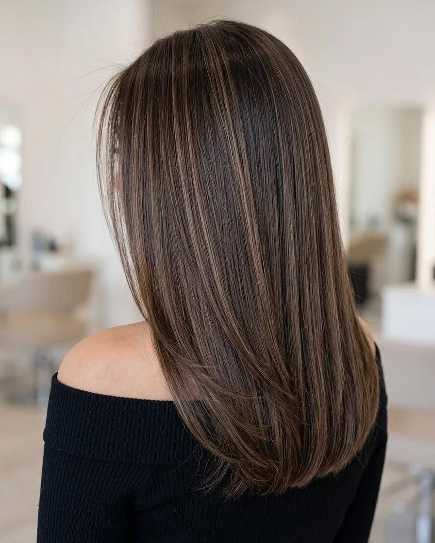 Dark brown shoulder-length hair with delicate blonde babylights in a salon